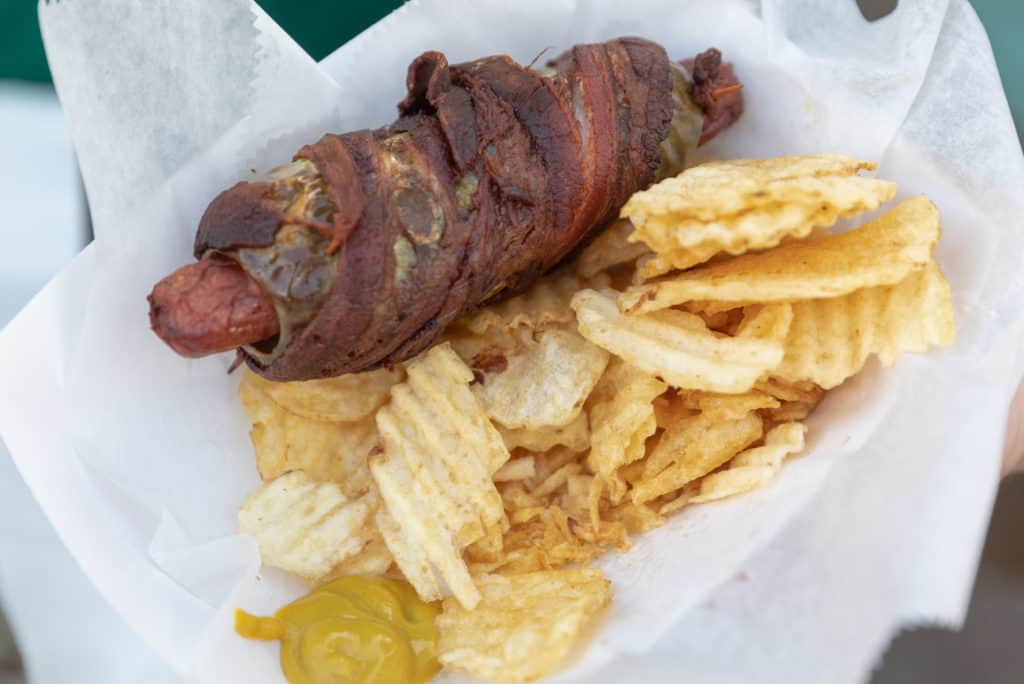 A bacon-wrapped stuffed pickle with a hot dog. 